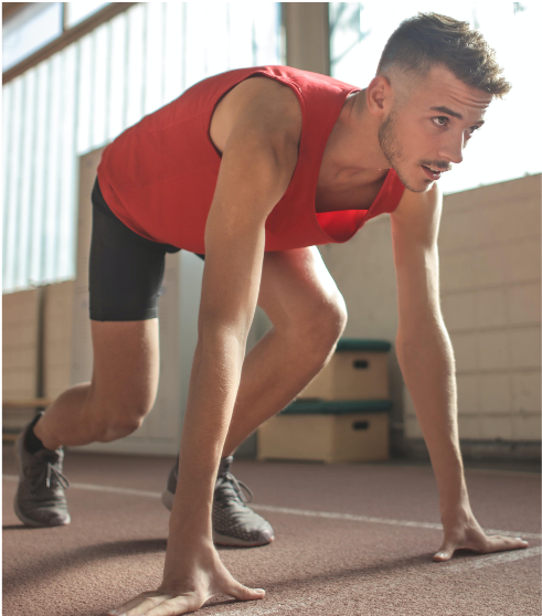 Man in red tank top in the starting position of a race.