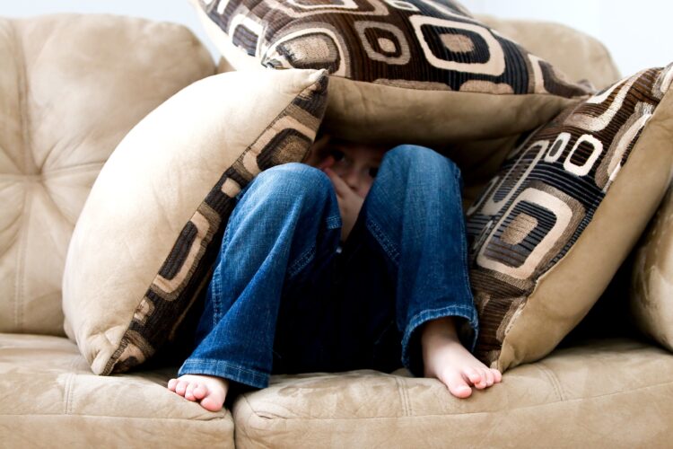 Child hiding in pillows but slightly peaking out