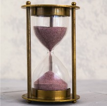 Hourglass with colorful purple sand to measure time.