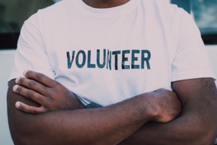 Man wearing a white T-shirt that says 'VOLUNTEER'.