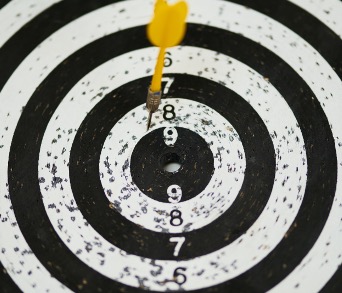 Black and white dartboard with yellow dart.