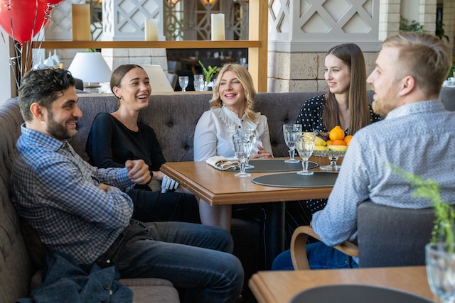 A group of friends sitting around at a restaurant and talking to each other.