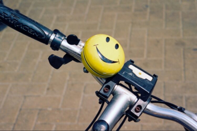Close up of bike handles with a yellow smiley face bell.