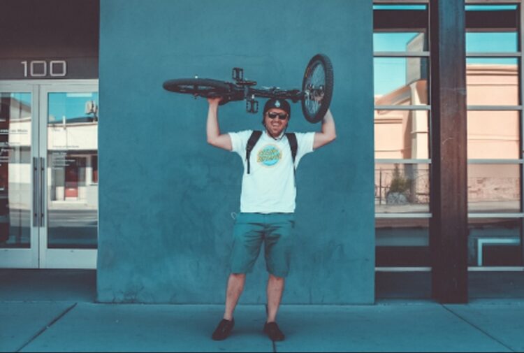 Man holding a bike over his head and smiling.